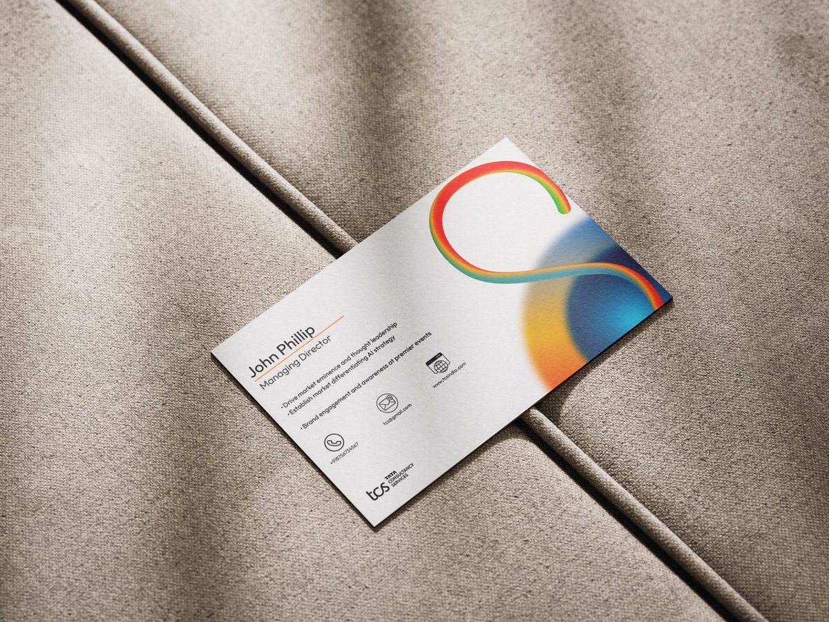 A business card lying flat on grey fabric, showing the circular gradient mark.